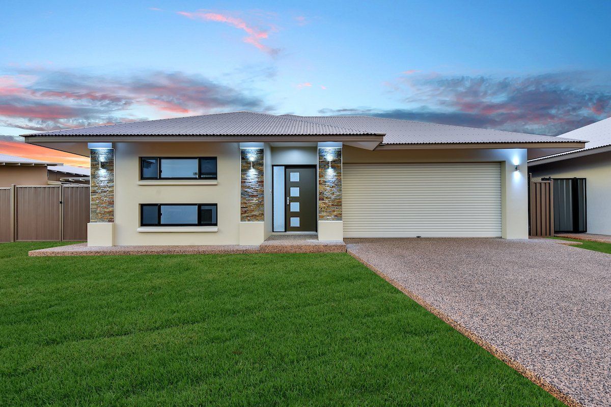 A house with a large driveway and a large lawn in front of it.