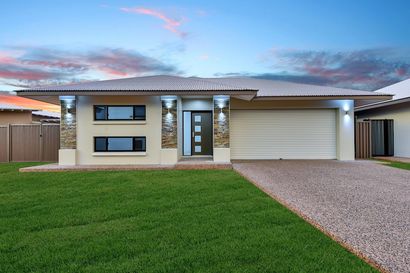 A house with a large driveway and a large lawn in front of it.