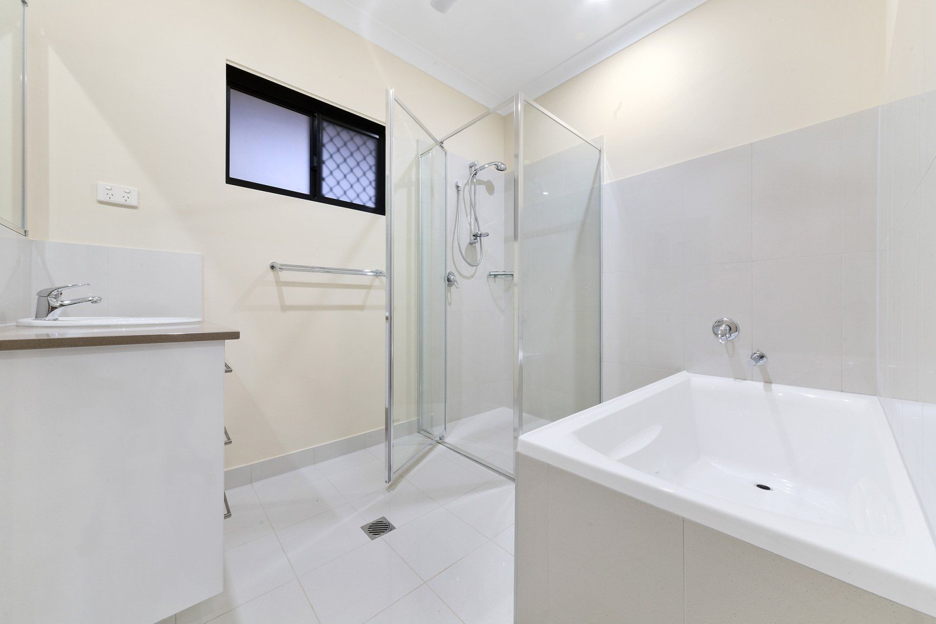 A bathroom with a bathtub , sink , shower and window.