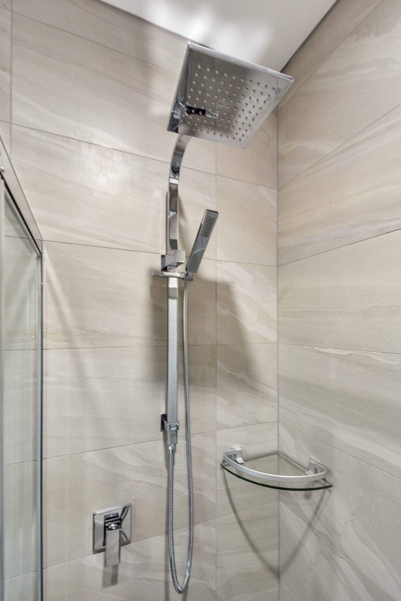 A shower head is hanging from the ceiling in a bathroom.