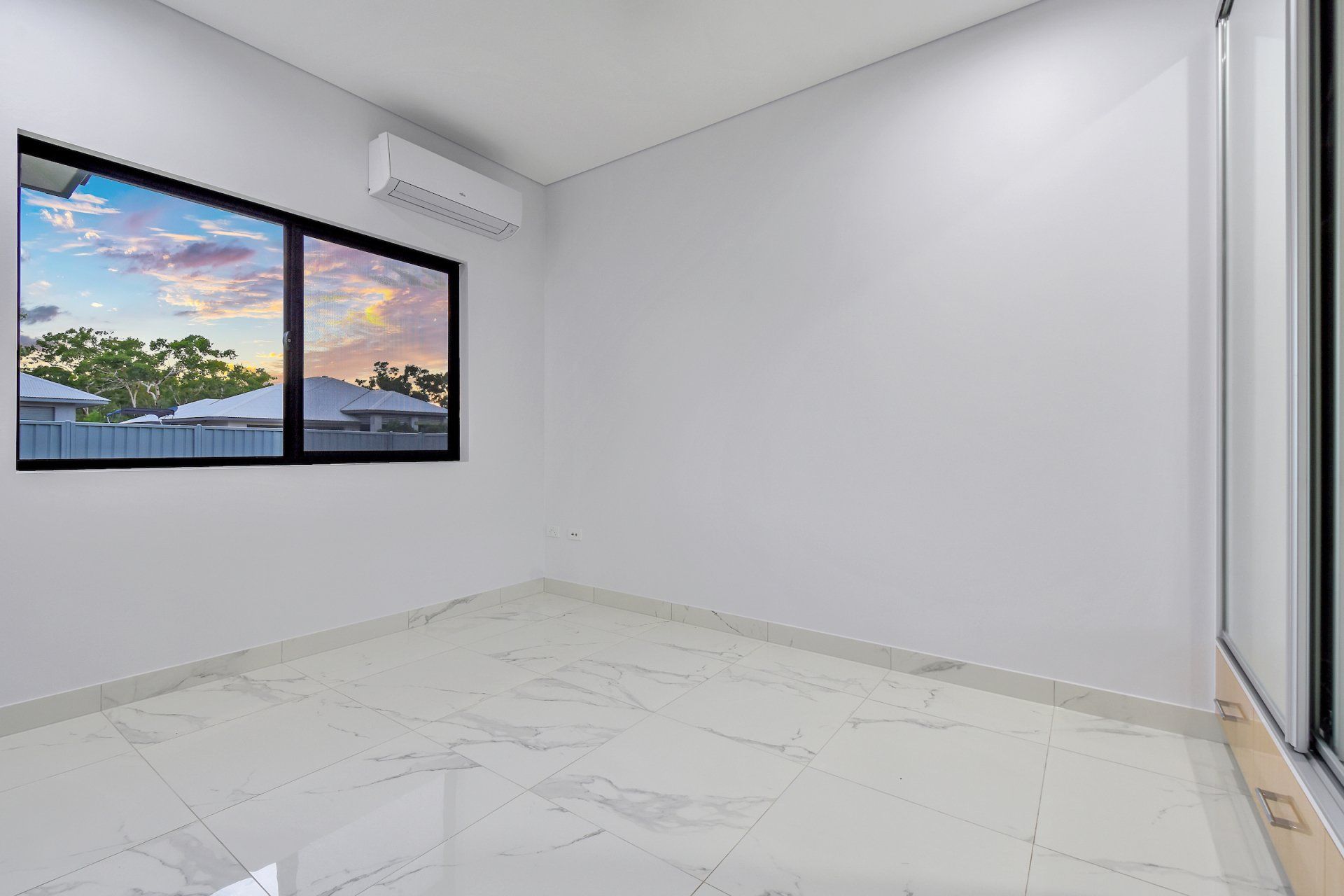 An empty room with two windows and a marble floor.