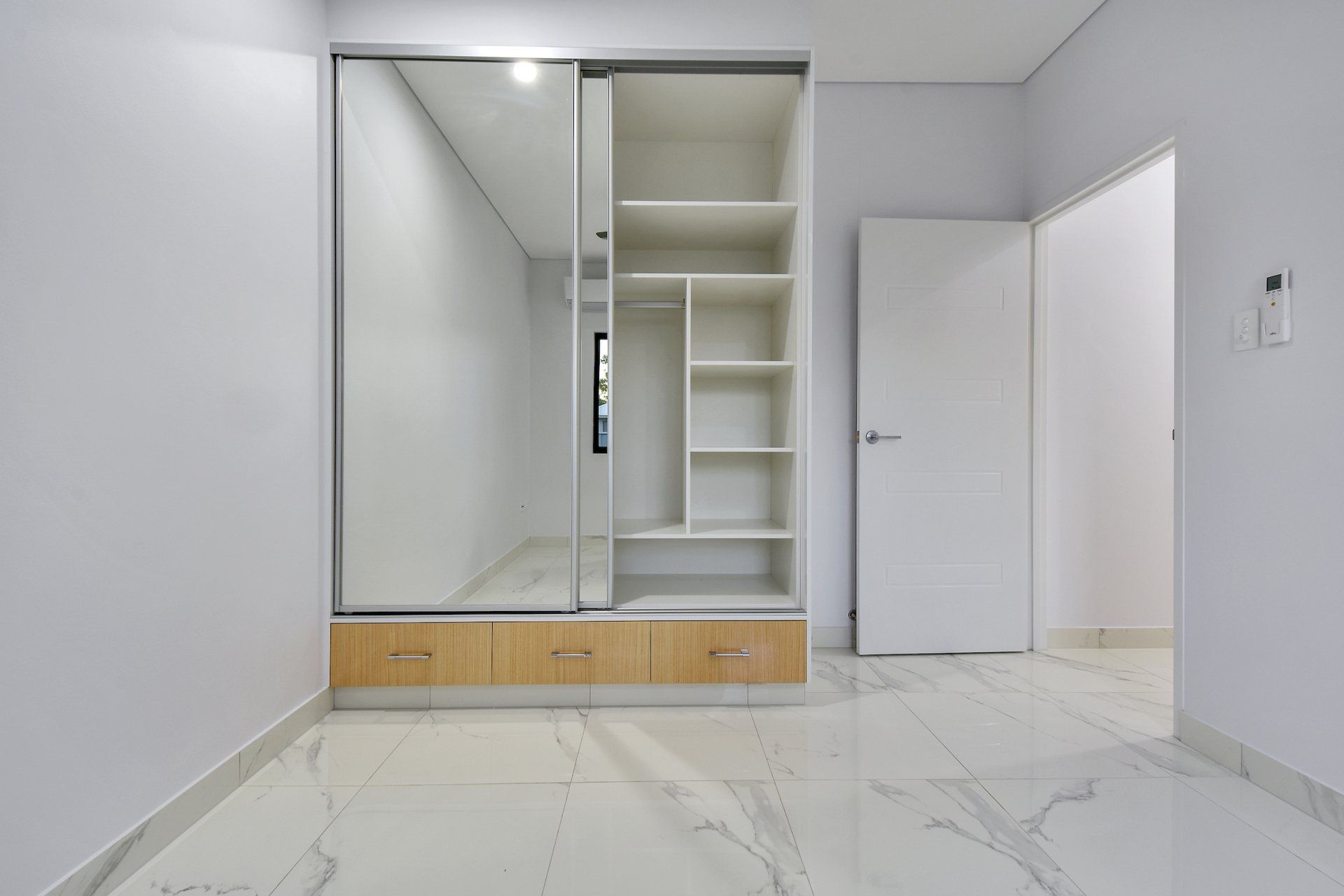 An empty room with a sliding glass door and a mirrored wardrobe.