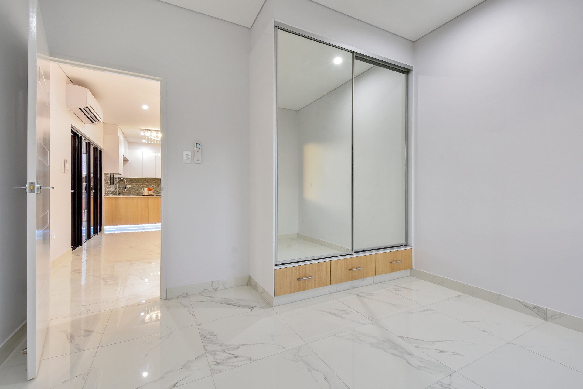 An empty room with a sliding glass door and a mirrored wardrobe.
