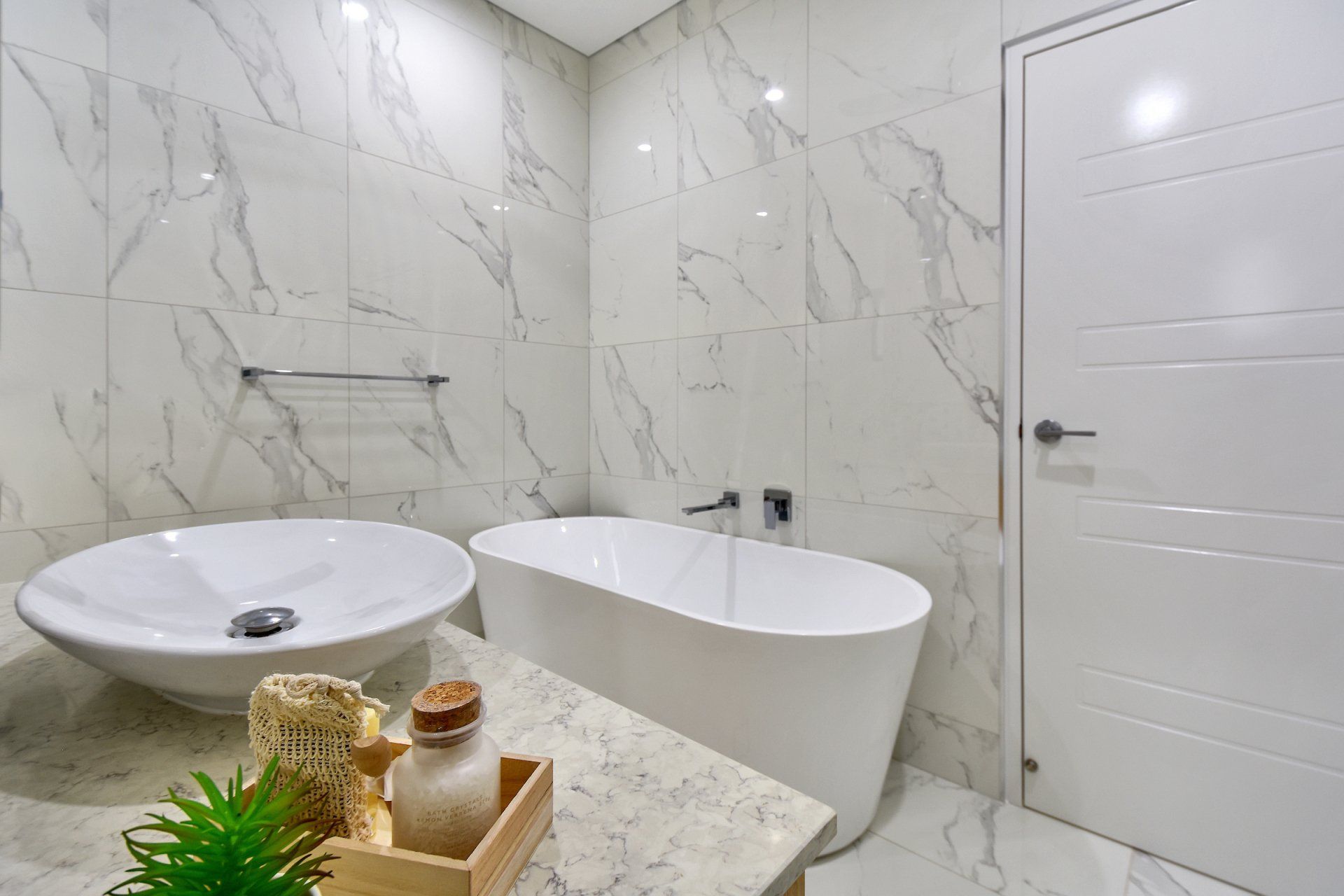 A bathroom with a bathtub , sink , and marble tiles.