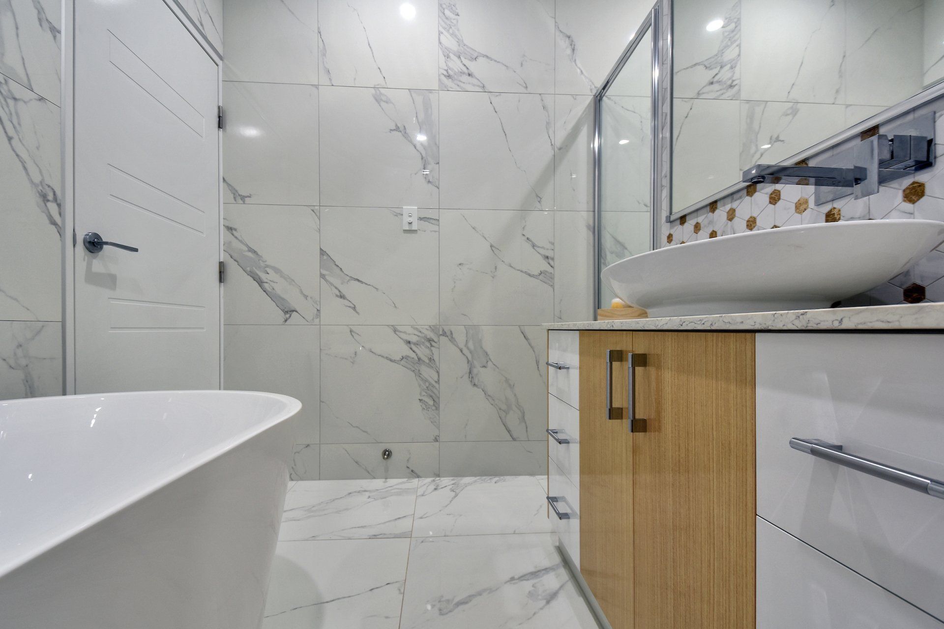 A bathroom with marble tiles , a sink , and a bathtub.