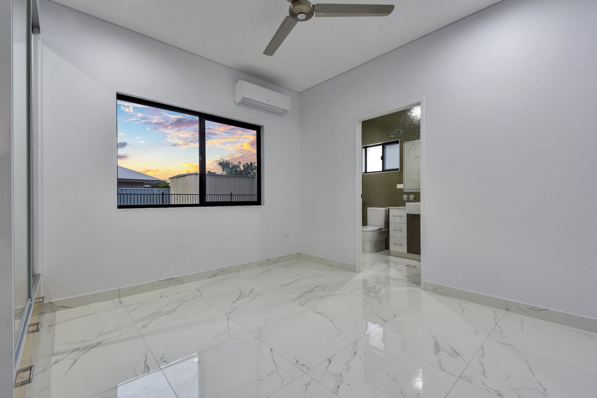 An empty room with a ceiling fan and a window.