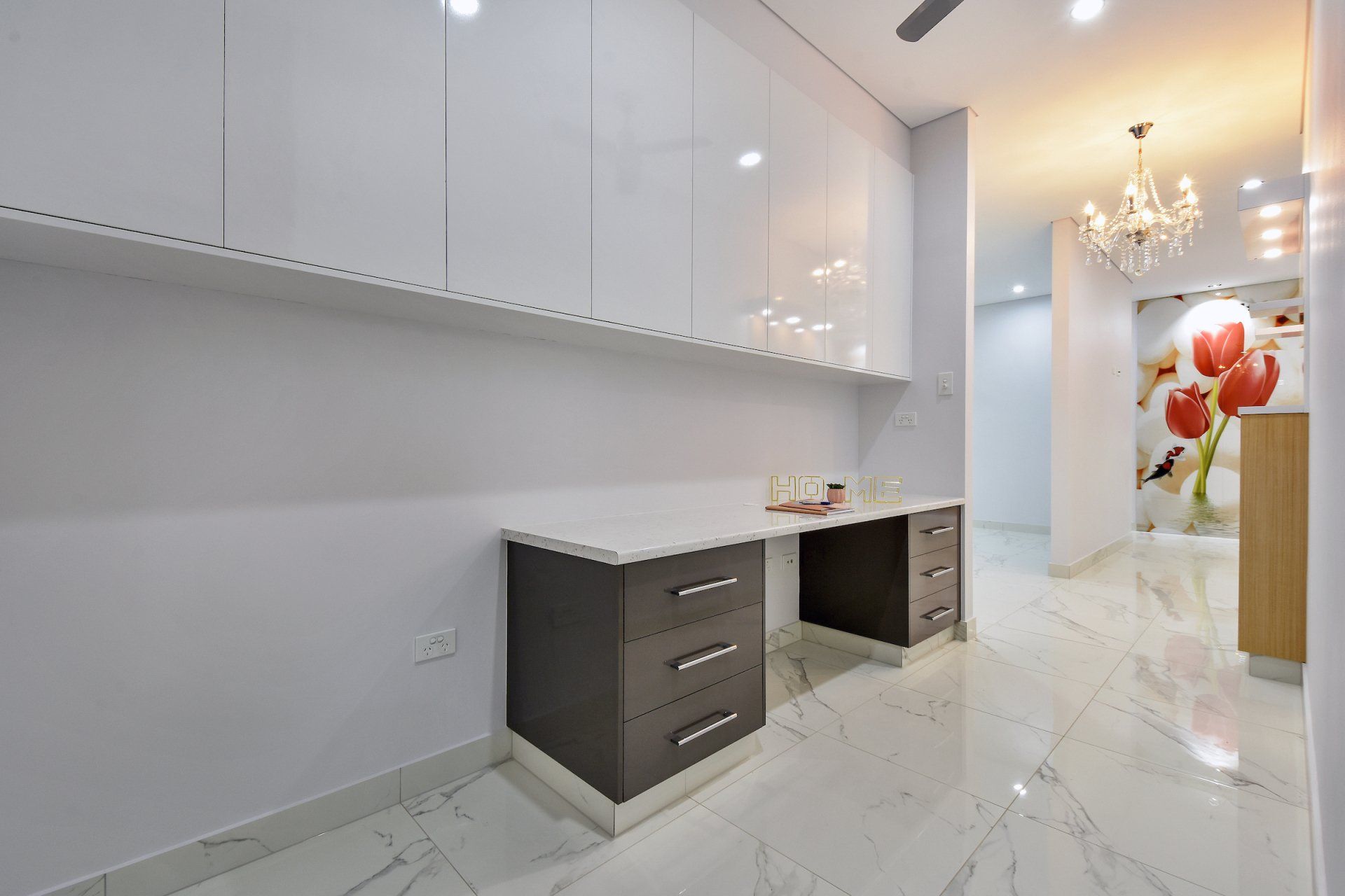 A room with a desk , cabinets , drawers and a chandelier.