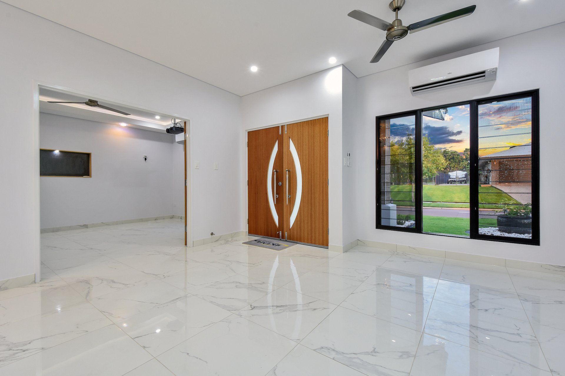 An empty living room with a ceiling fan and a marble floor.