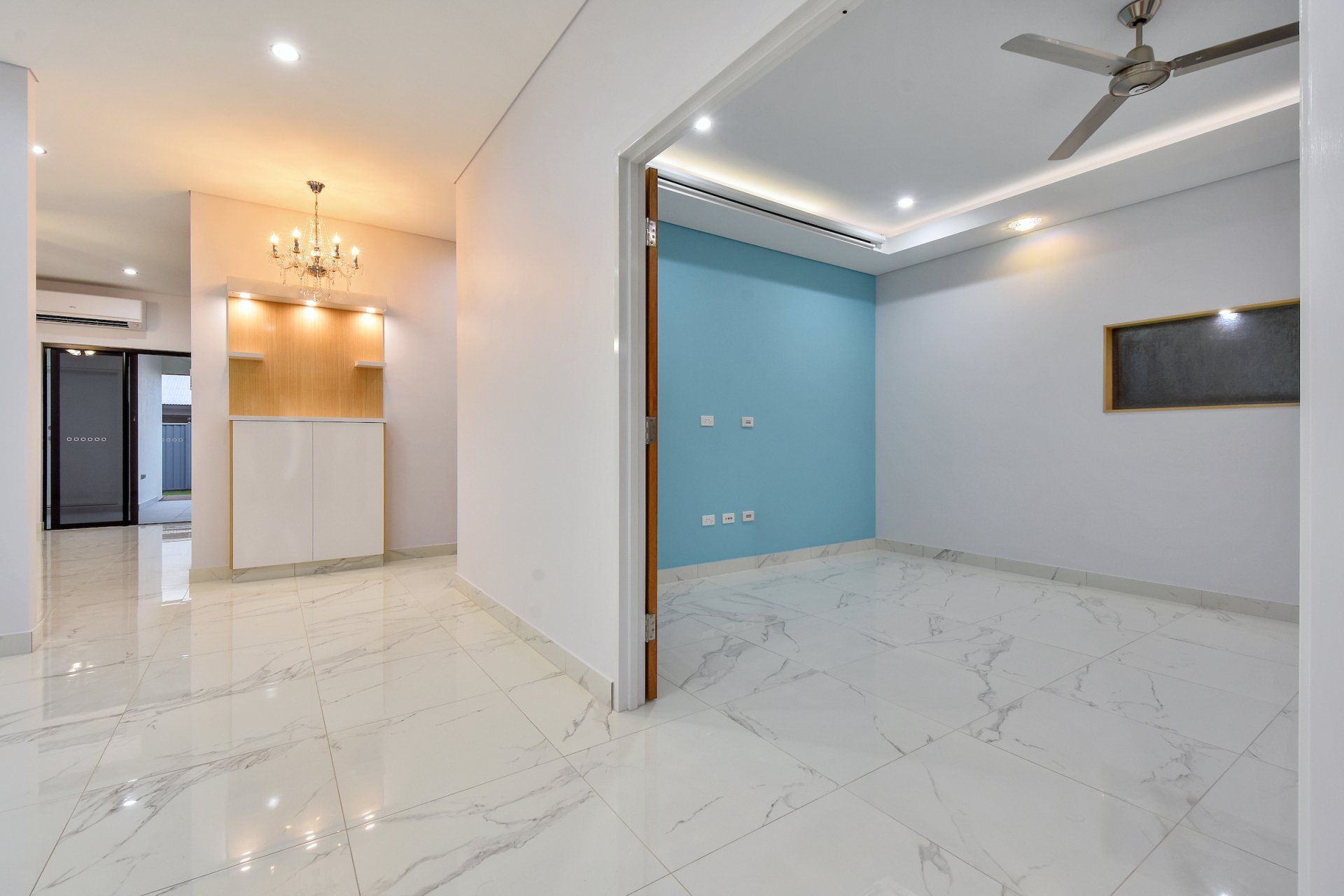 An empty room with a ceiling fan and a blue wall