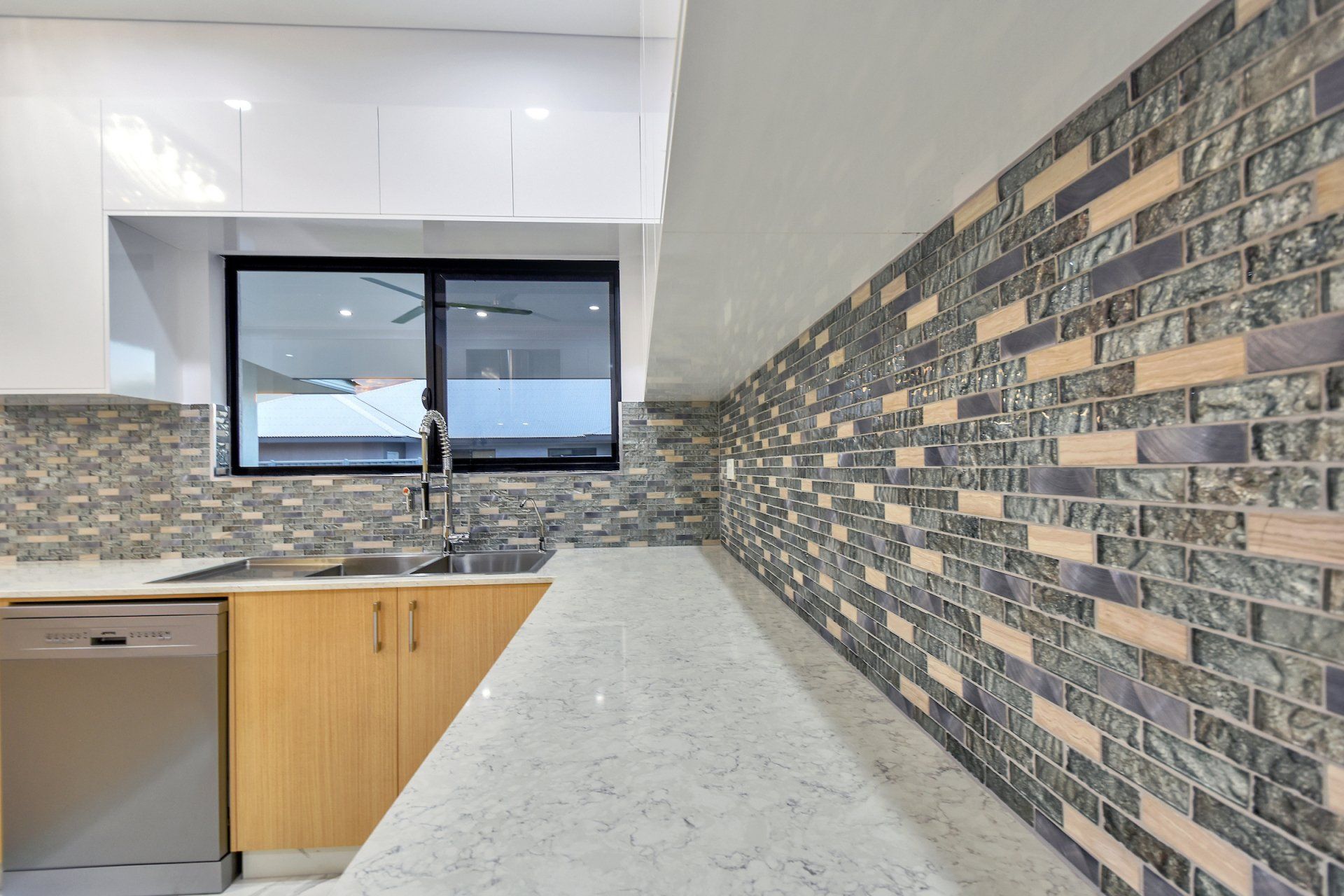 A kitchen with a brick wall and a stainless steel dishwasher