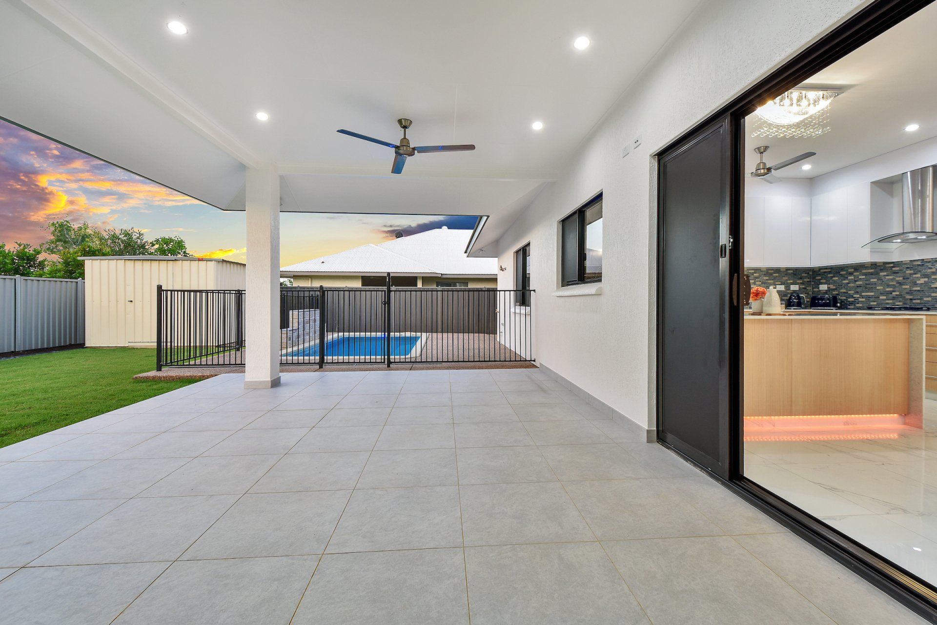 A patio with a sliding glass door and a pool in the backyard of a house.