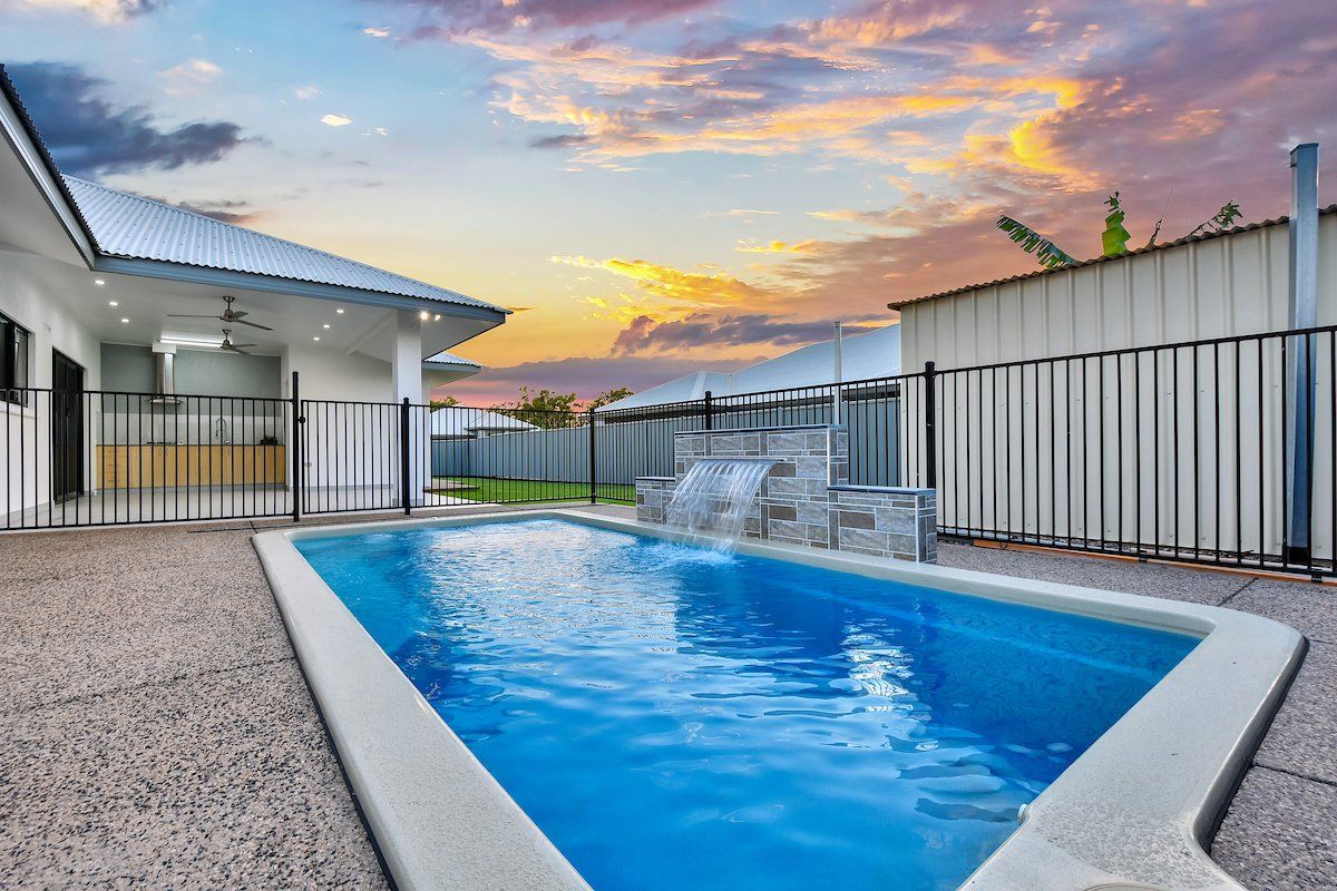 There is a large swimming pool in the backyard of a house.