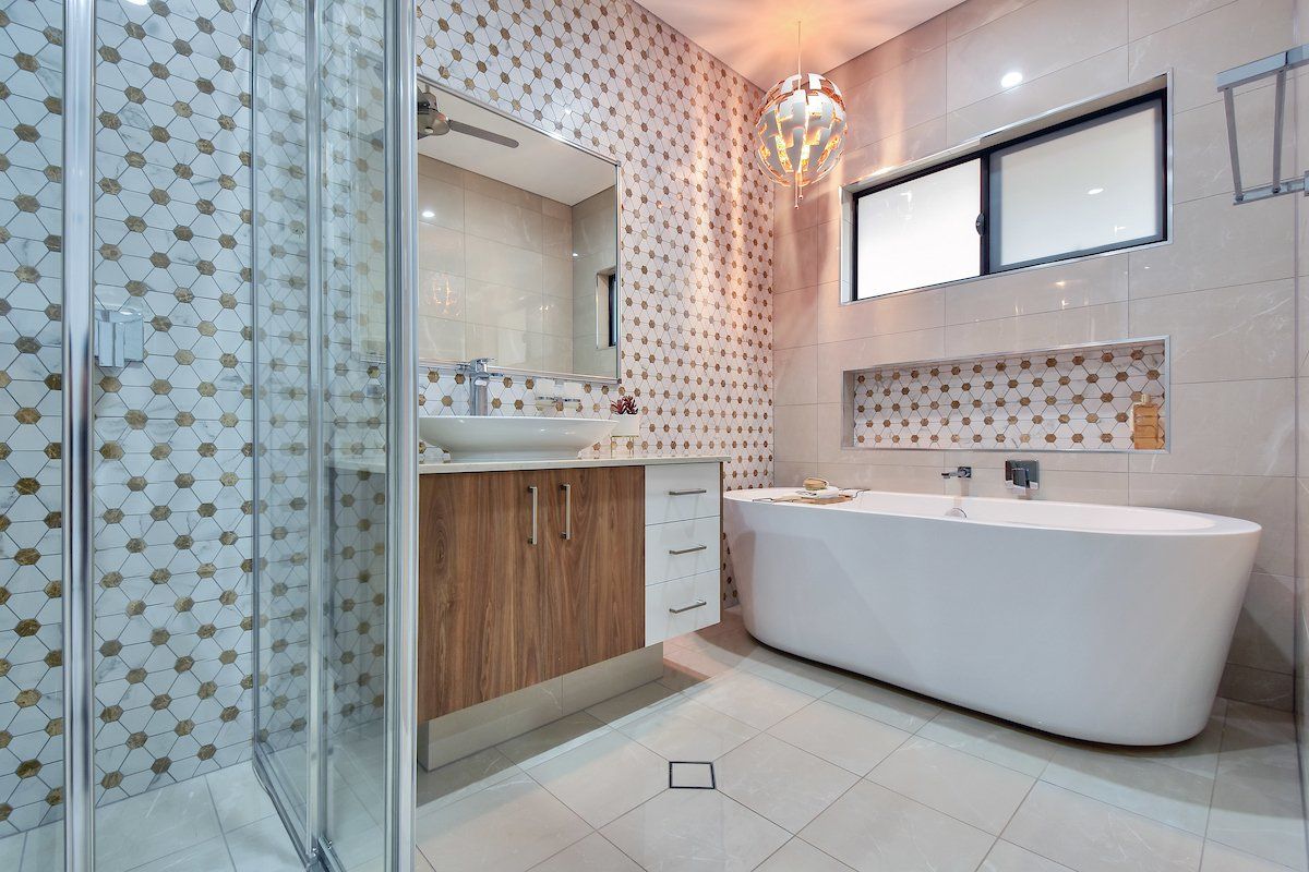 A bathroom with a tub , sink , mirror and shower.