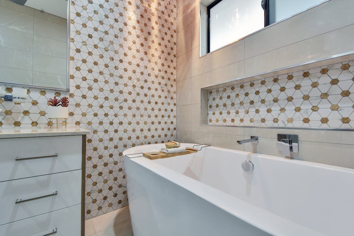 A bathroom with a bathtub , sink , mirror and window.