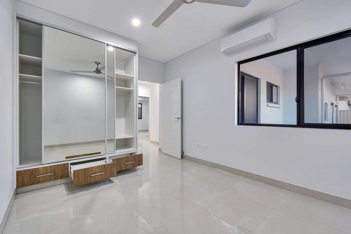 An empty bedroom with a ceiling fan and a large mirrored wardrobe.