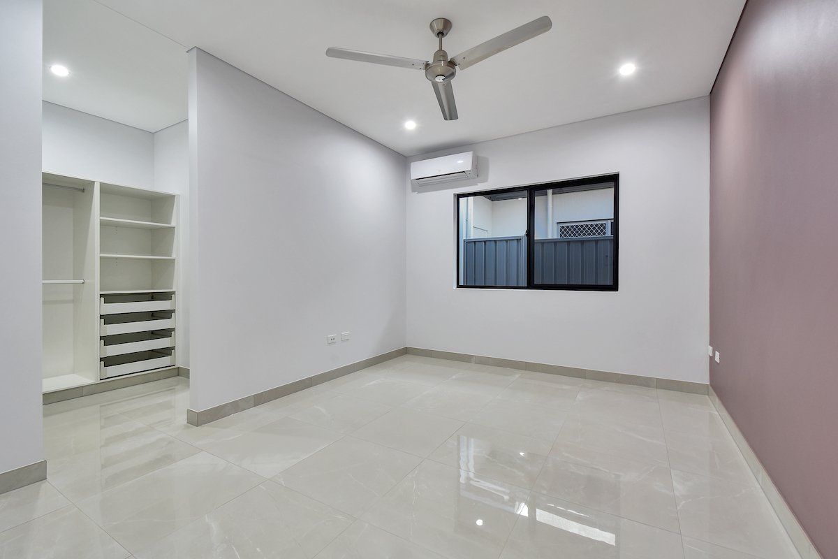 An empty room with a ceiling fan and a window.