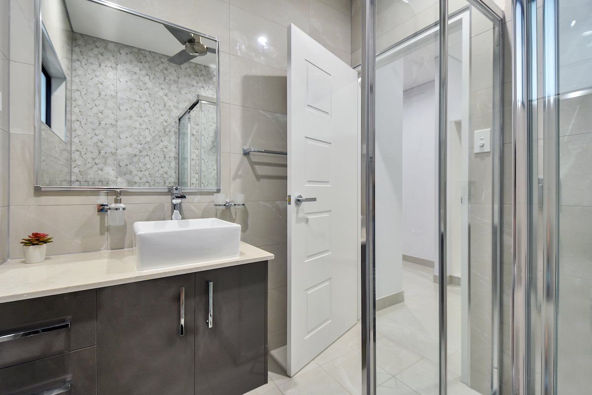 A bathroom with a sink , mirror , and walk in shower.