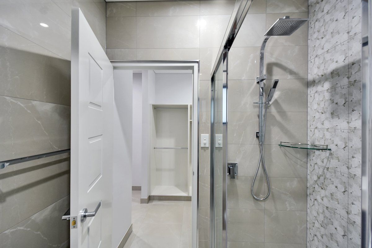 A bathroom with a walk in shower and a door open.