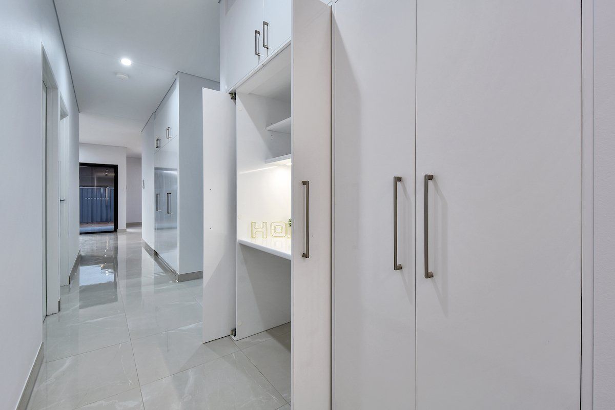 A hallway with white cabinets and a shelf in the middle of it.