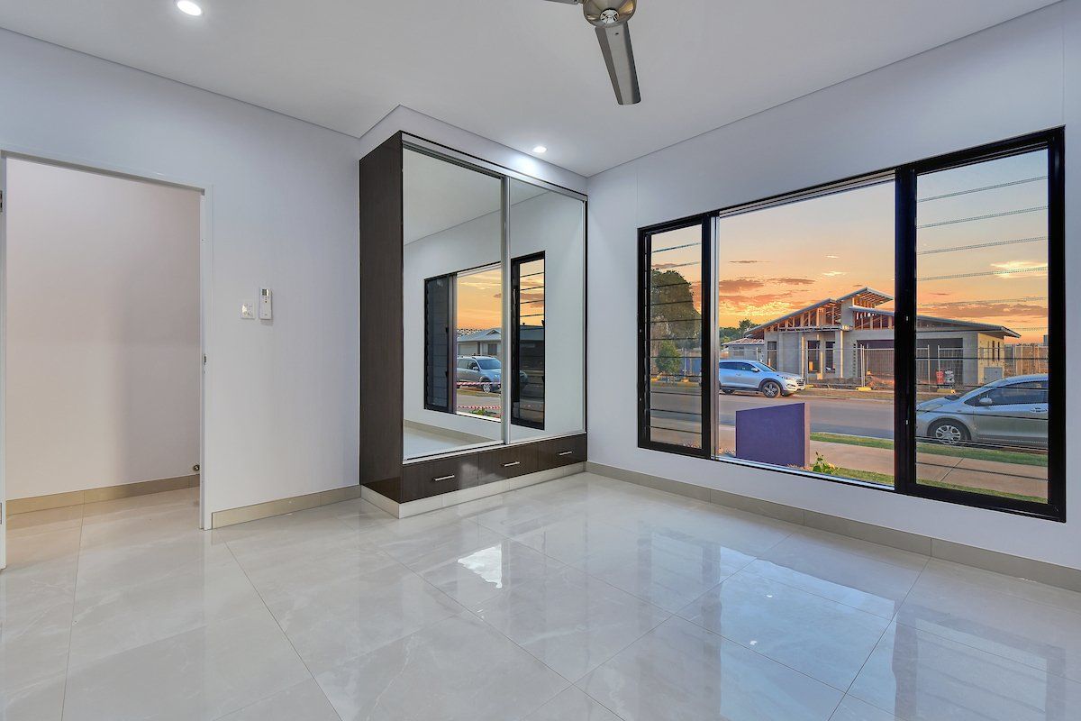 An empty room with a lot of windows and a ceiling fan.