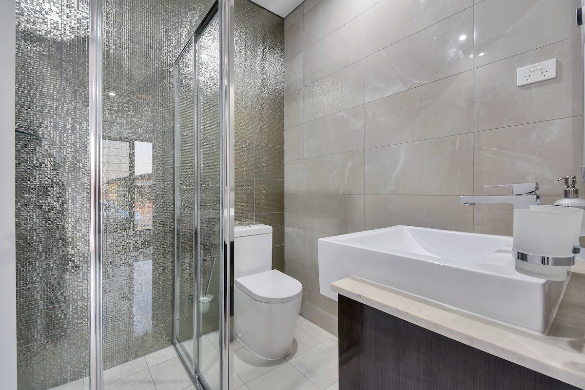 A bathroom with a toilet , sink and walk in shower.