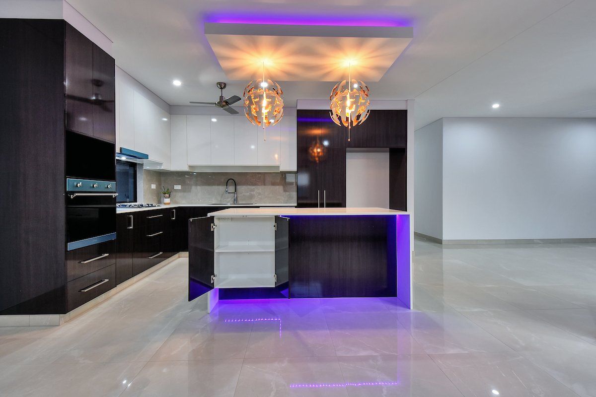 A kitchen with purple lights hanging from the ceiling