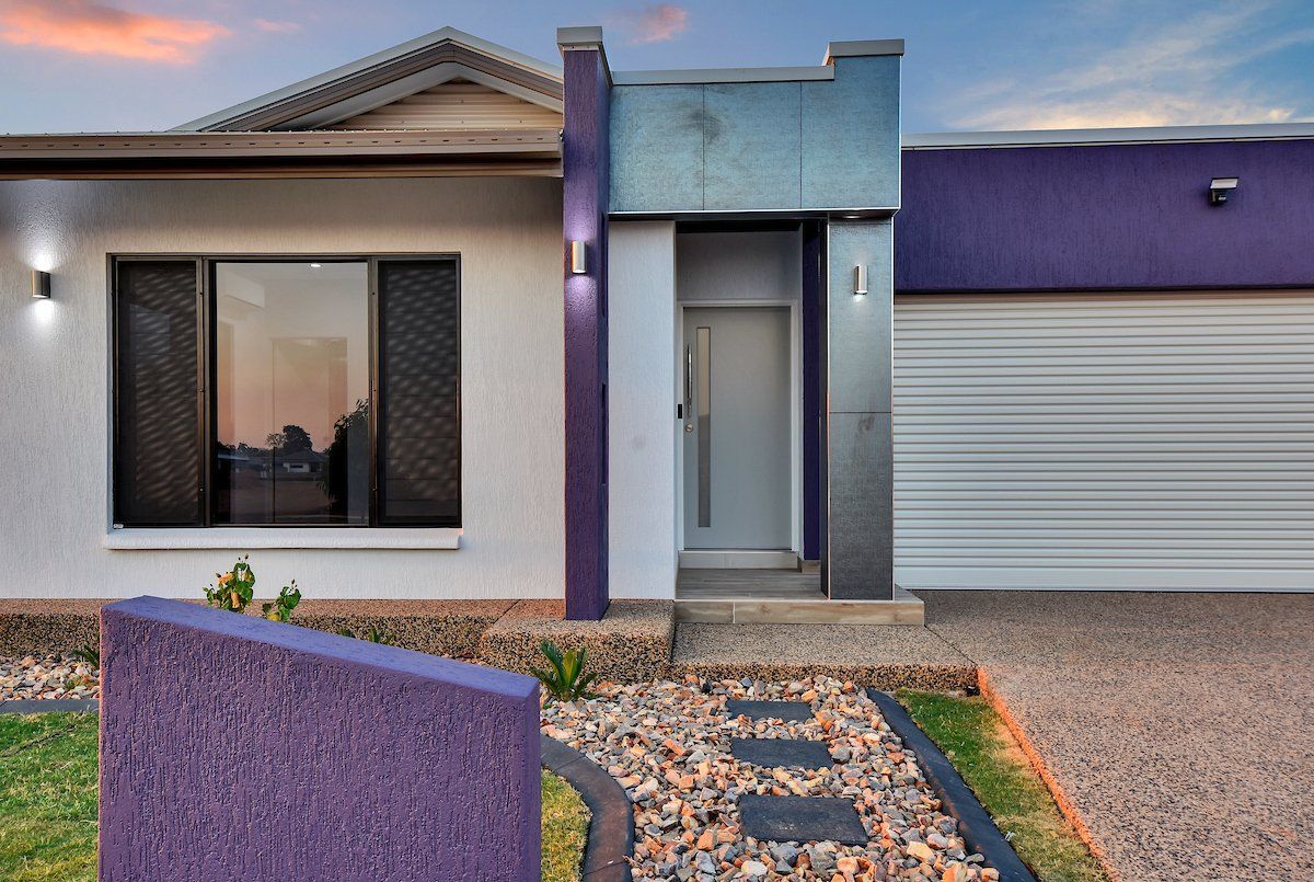 A white house with purple trim and a purple wall