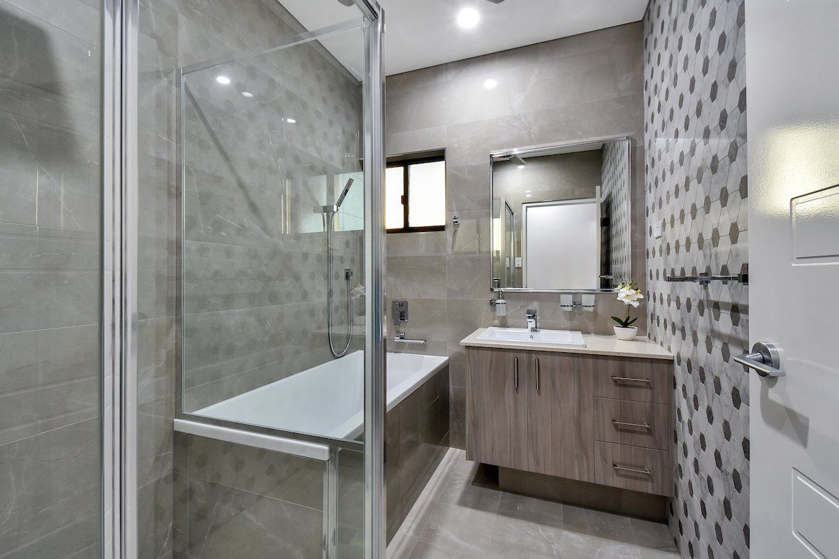 A bathroom with a bathtub , sink , mirror and walk in shower.