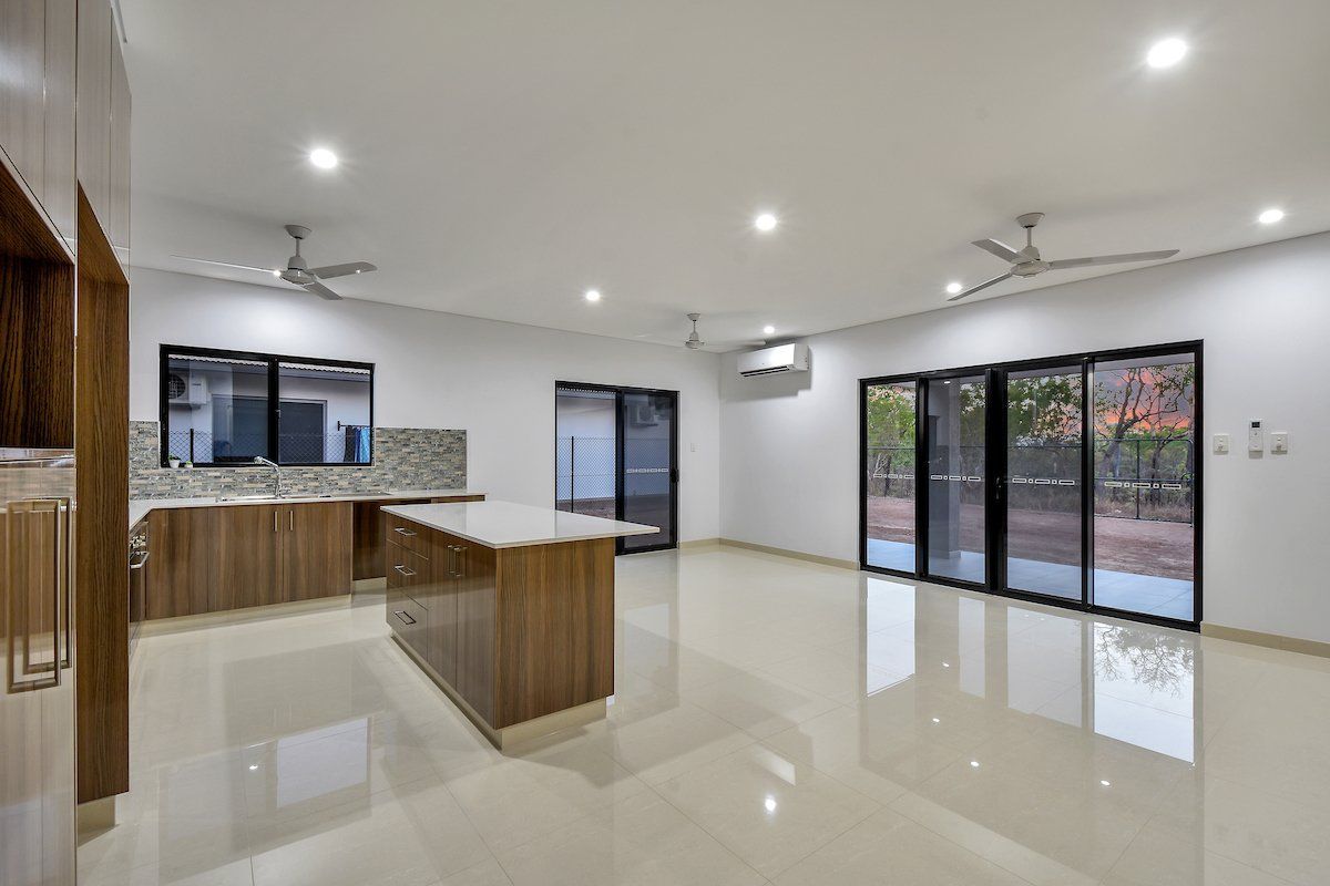 A large empty room with a kitchen , living room , and sliding glass doors.