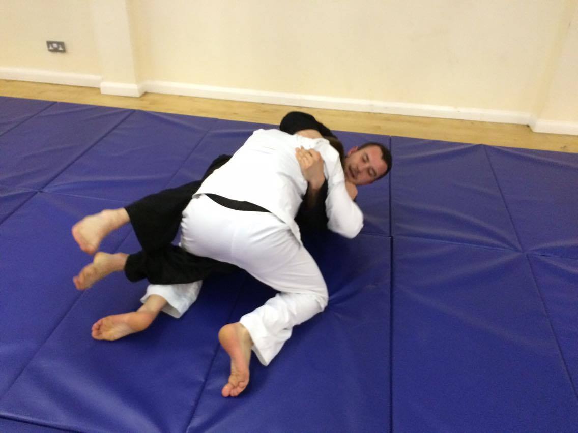 Two men are wrestling on a blue mat in a gym