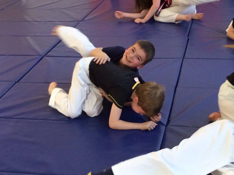 Two boys are wrestling on a blue mat