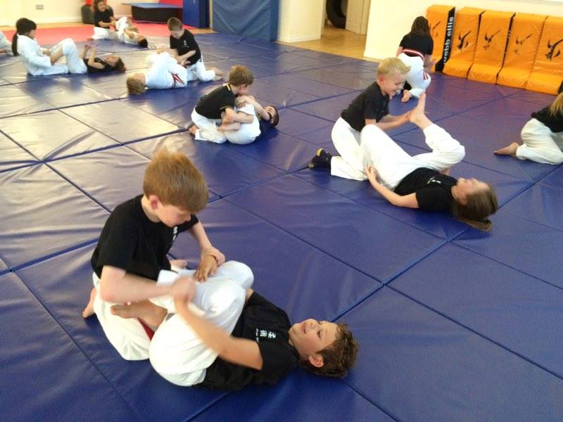A group of children are practicing martial arts on a mat