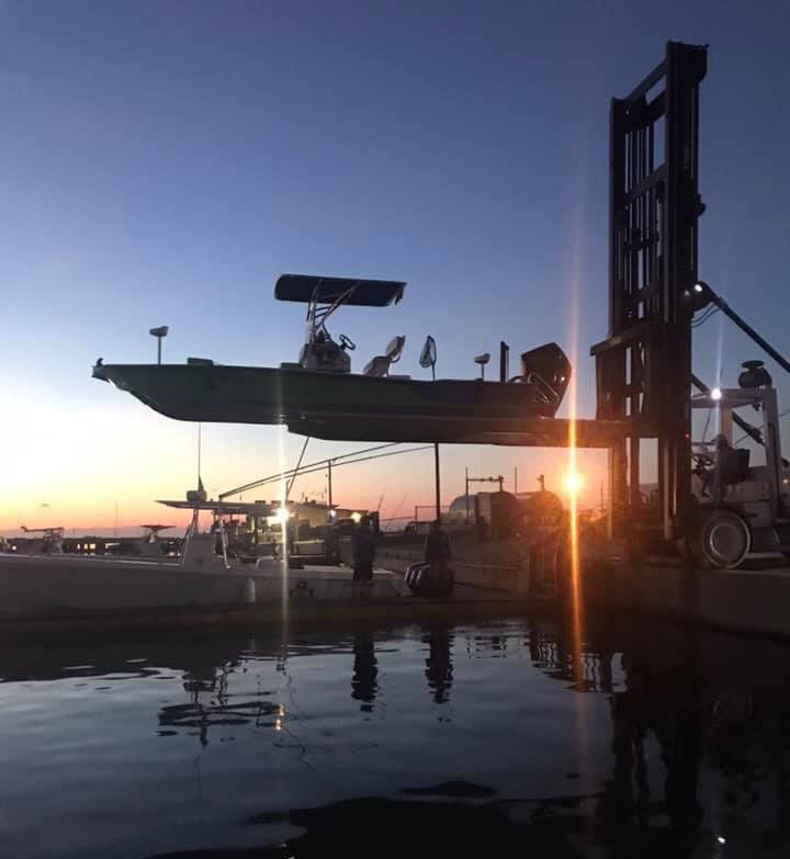 A boat is being lifted into the water by a forklift
