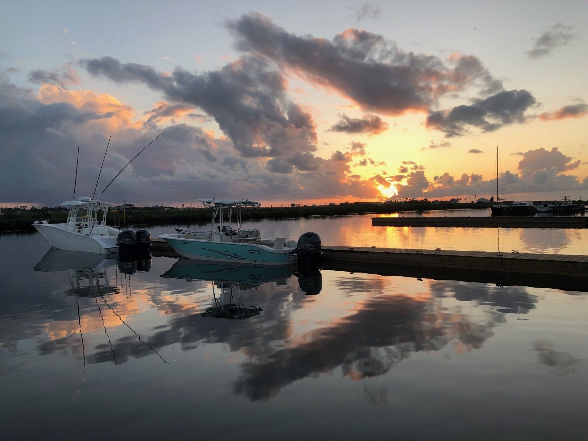 A couple of boats are docked in a harbor at sunset.