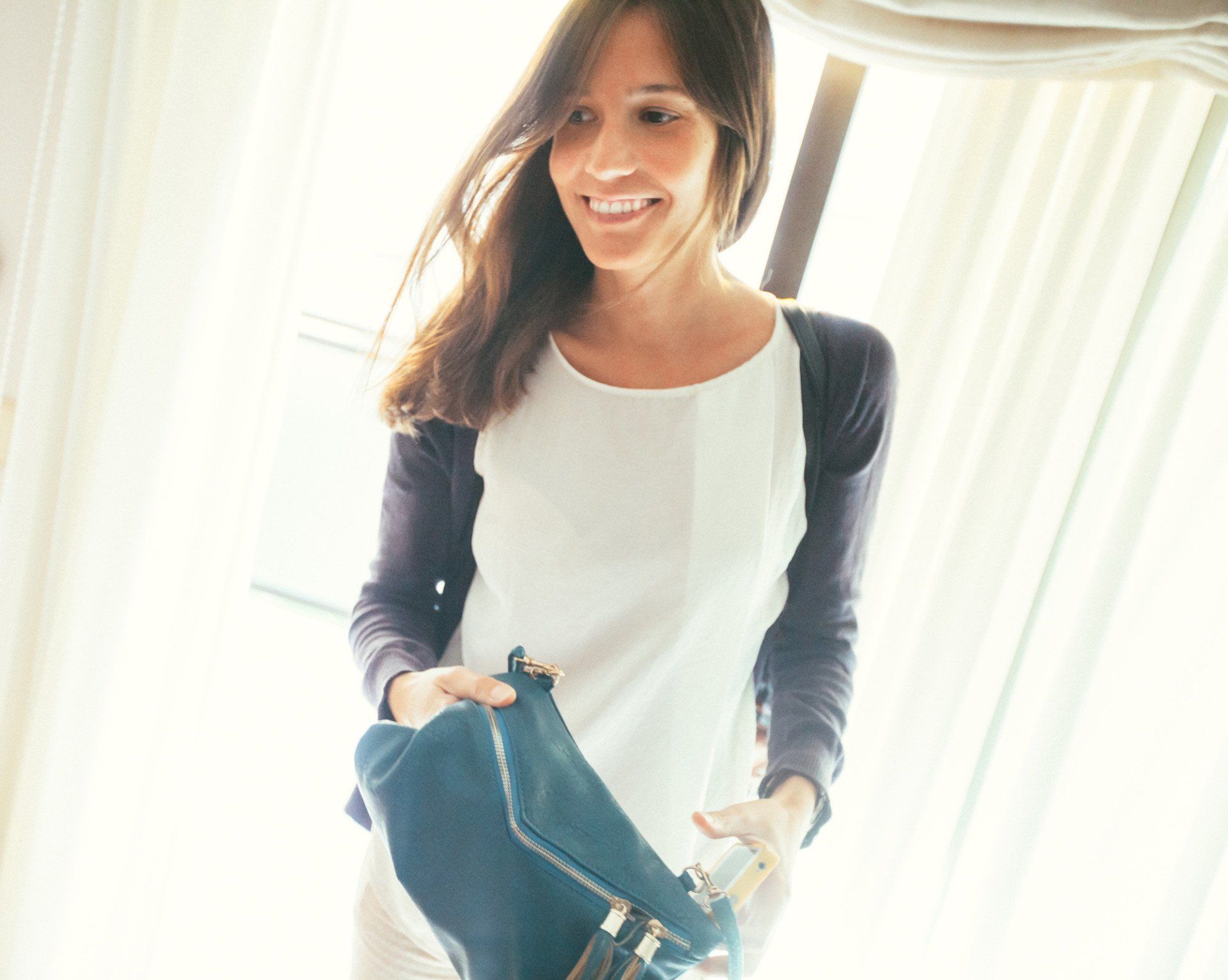 Pretty smiling woman holding purse indoors