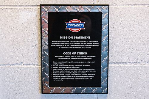 A sign on a brick wall with a logo, mission statement, and code of ethics from 