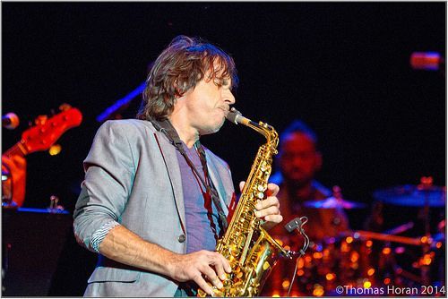 Musician playing saxophone onstage under blue and red lights