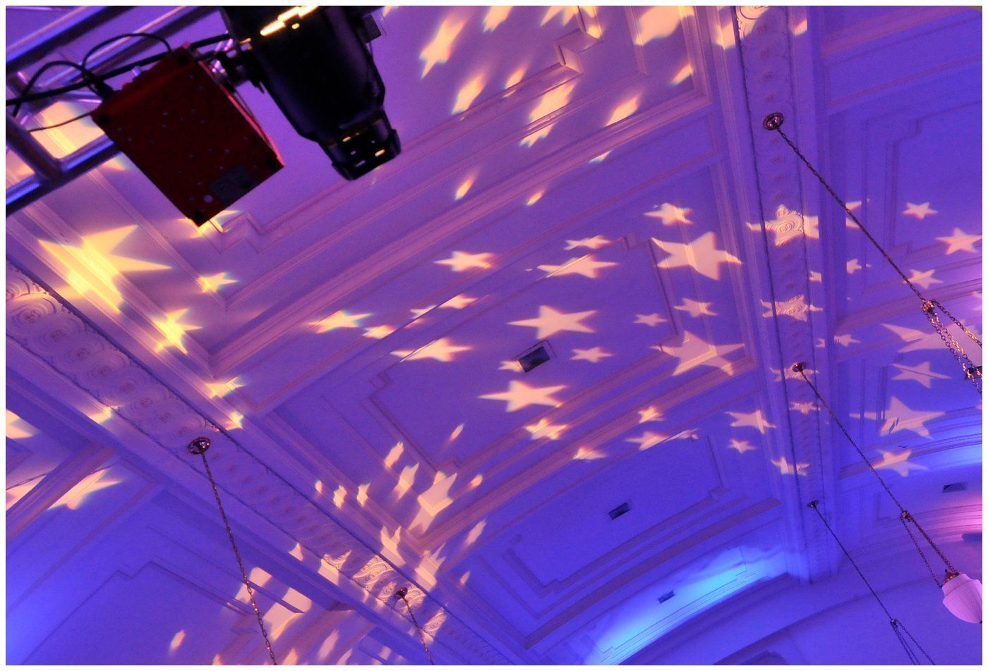 Ceiling lit in purple with star-shaped light projections and hanging stage lights