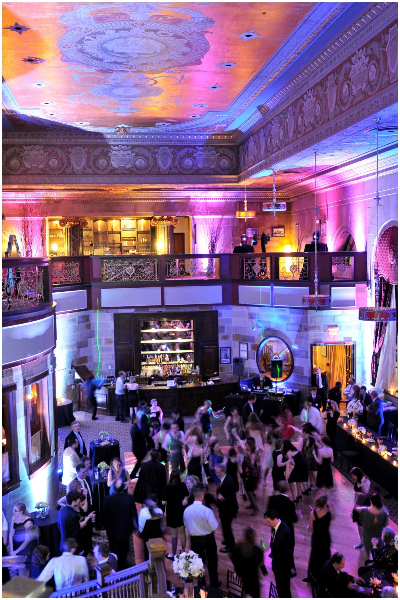 Crowded nightclub with dancers under pink and blue lights in an ornate ballroom
