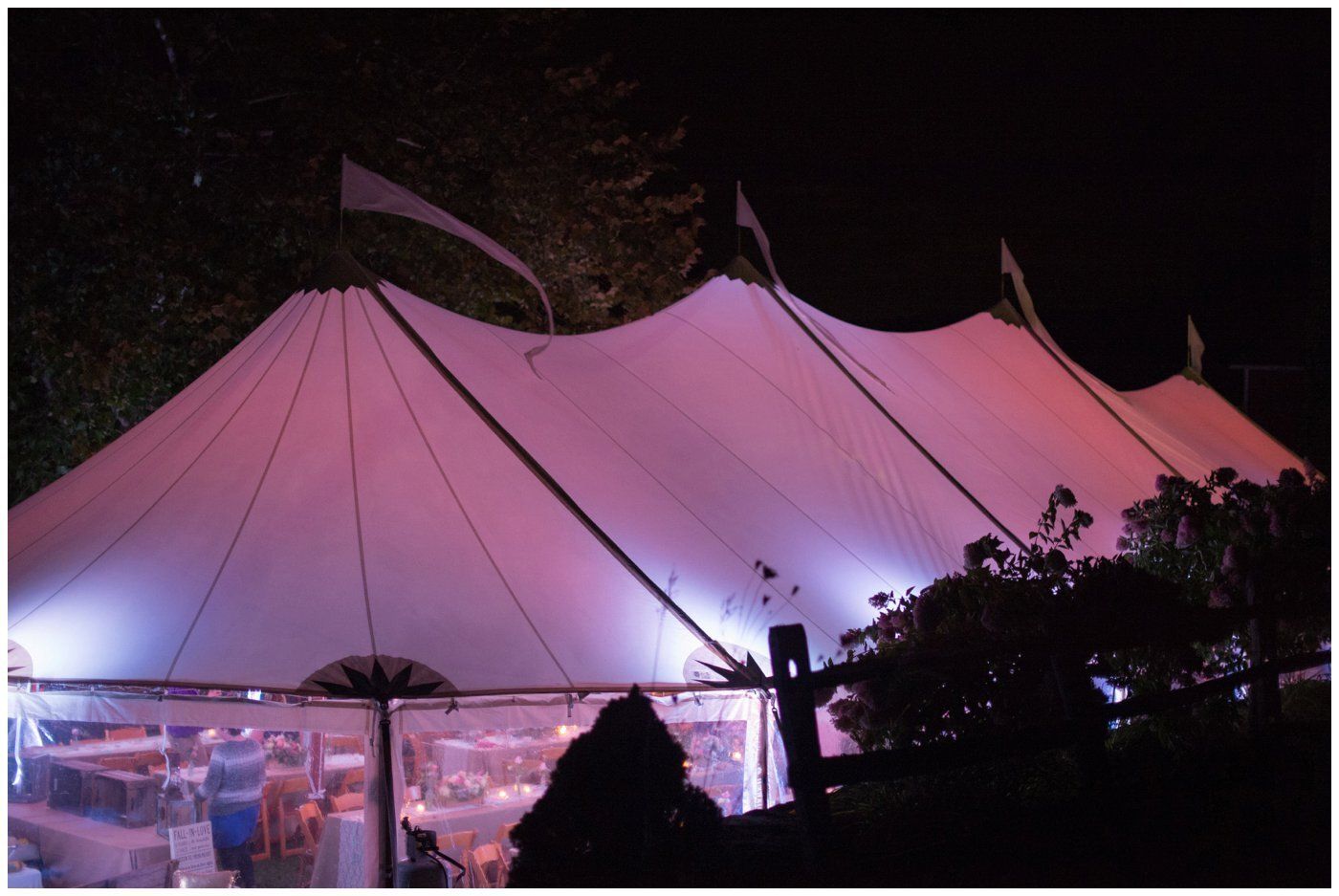 Pink-lit tent structure at night, with people visible inside near the bottom.