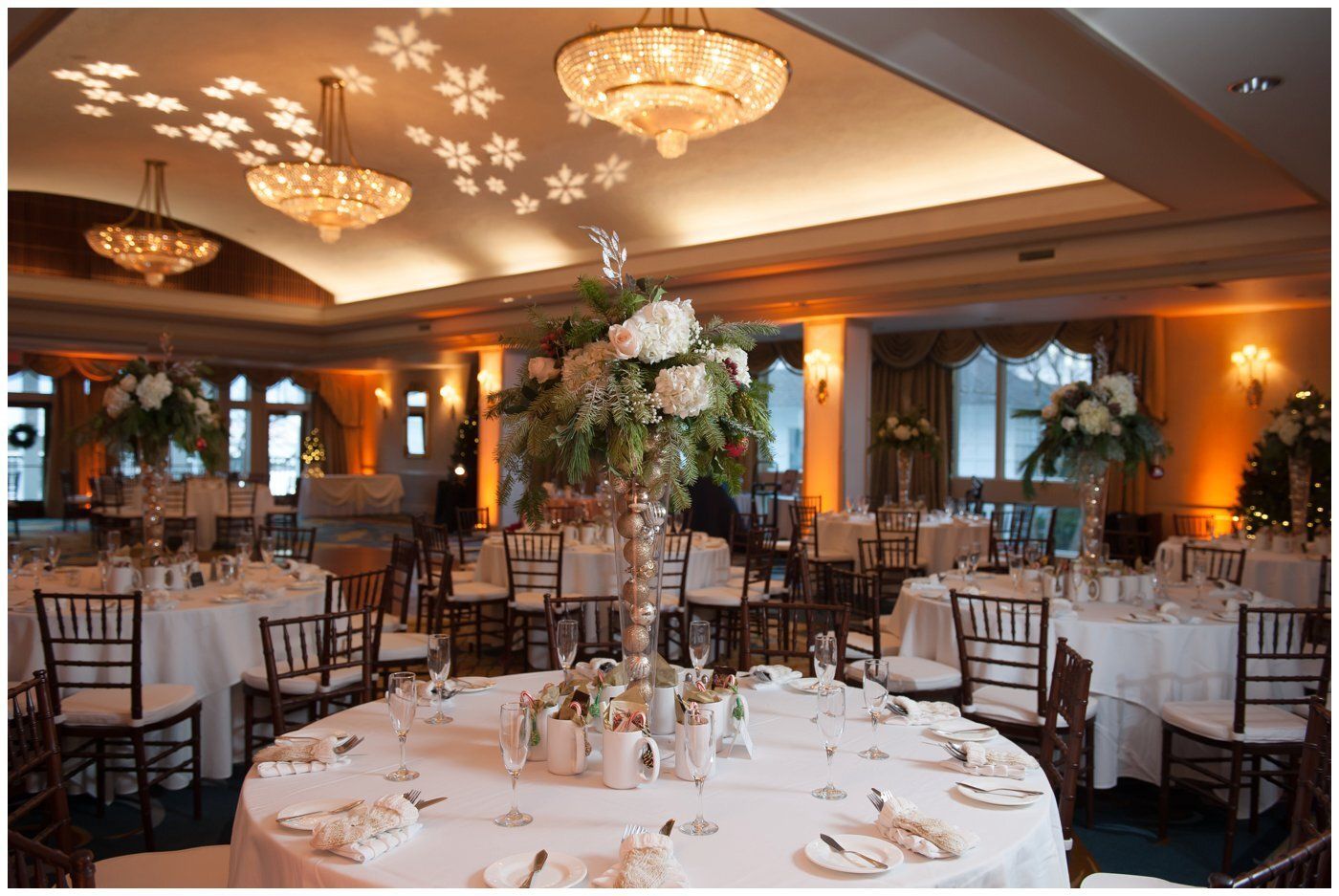 Elegant banquet hall with round white tablecloth tables, chandeliers, and floral centerpieces