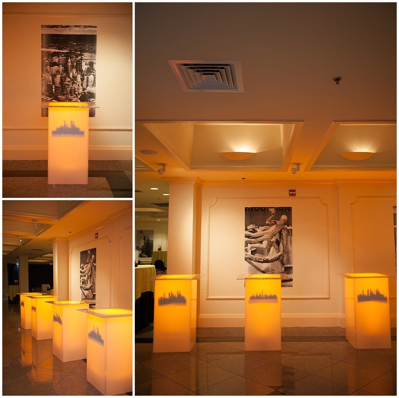Warm-lit gallery of illuminated display pedestals and framed black-and-white photos in a hallway.
