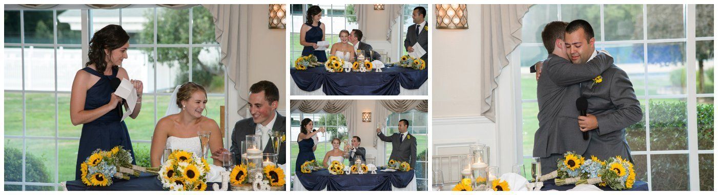 Guests chat at a bright table with sunflowers as two people hug near a window.