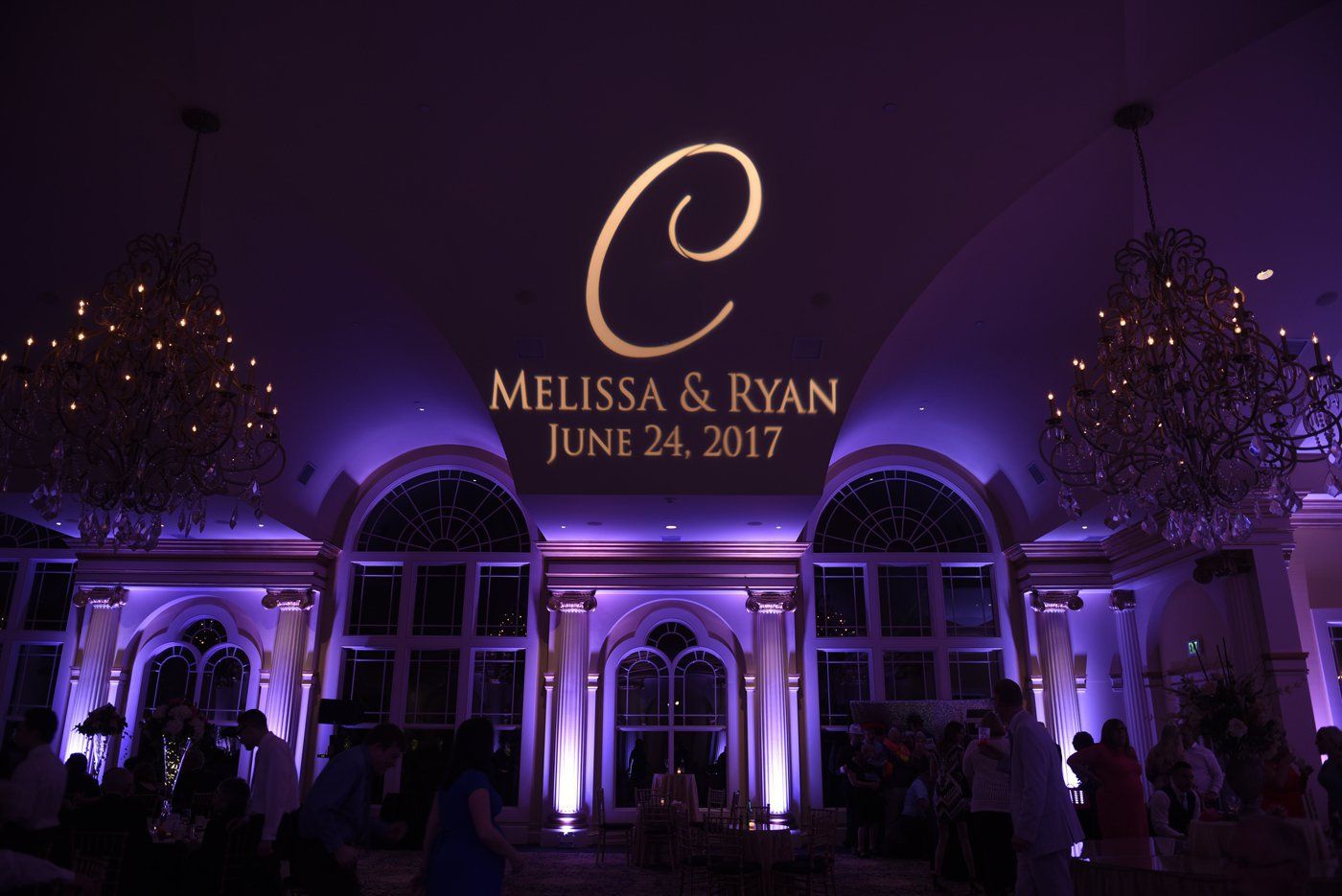Elegant wedding venue lit in purple with monogram “C” and text “Melissa & Ryan June 24, 2017”