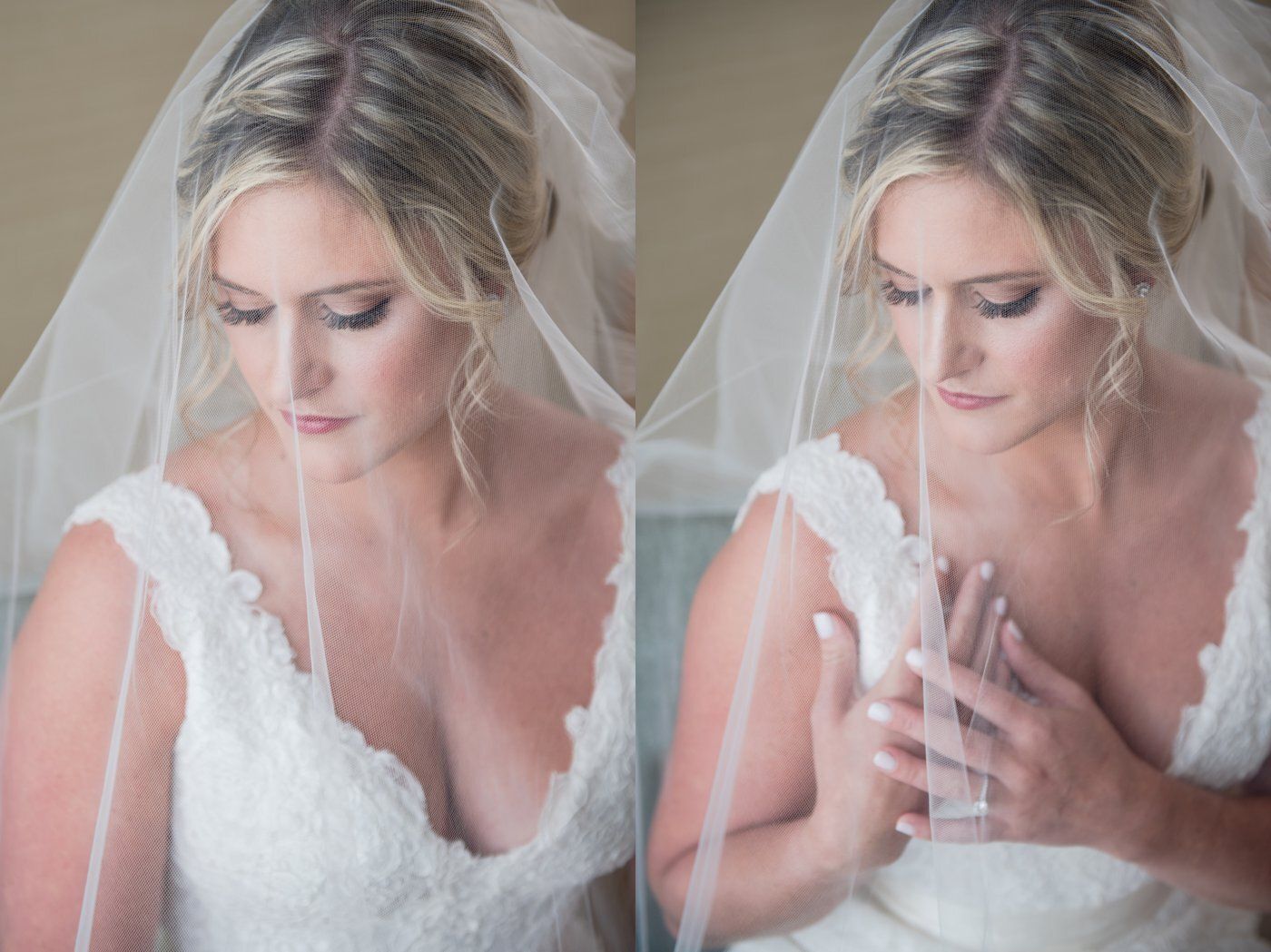Bride in white lace dress and veil, looking down with hands clasped in a soft, romantic portrait.