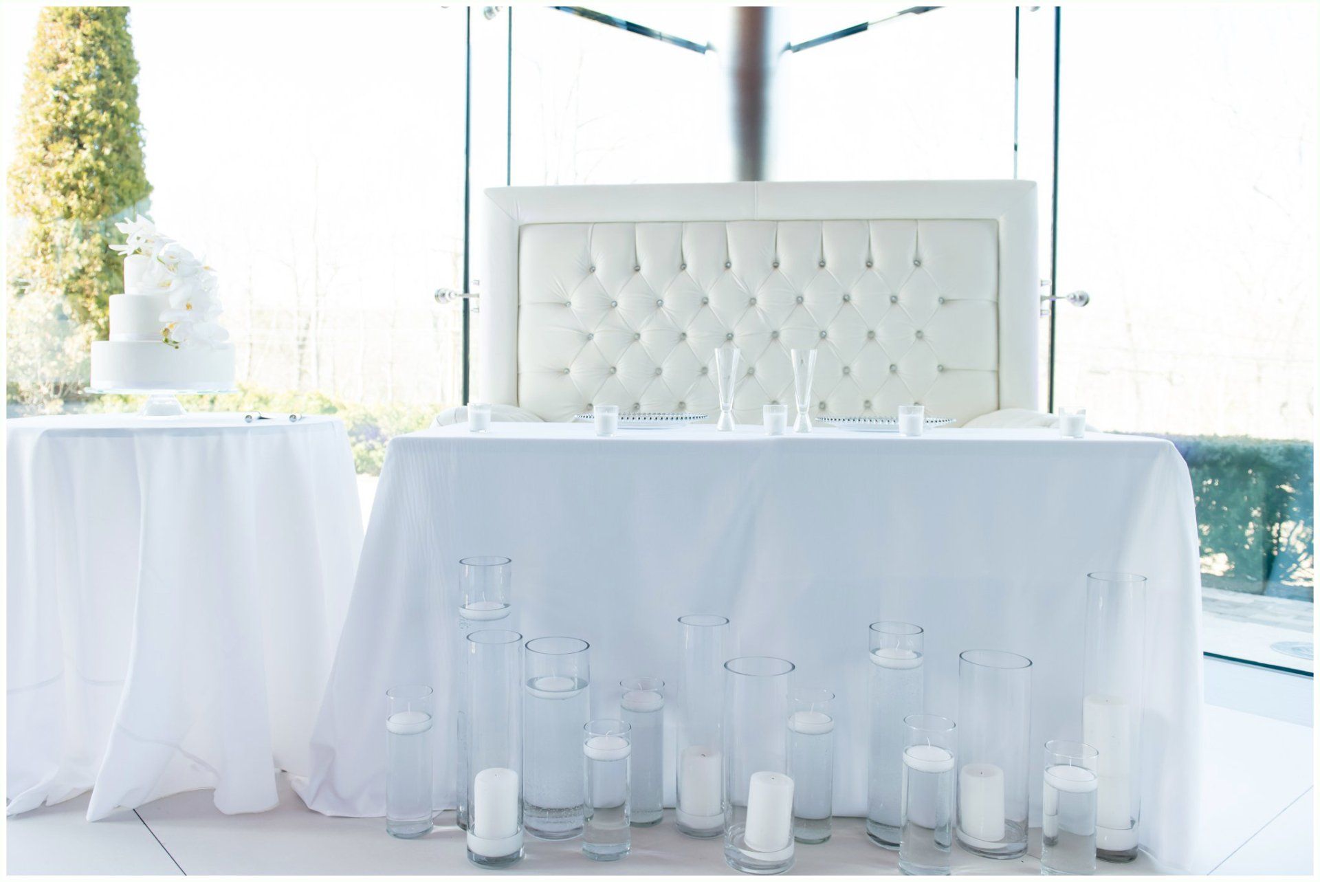 White-clothed event table with candles and a tufted chair in a bright room