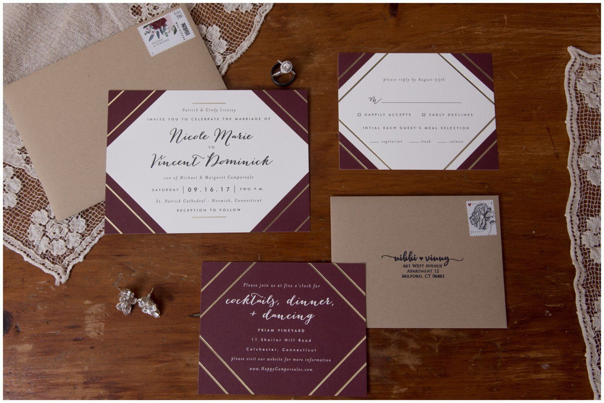 Wedding invitation suite on a wooden table with lace, in burgundy and blush tones.