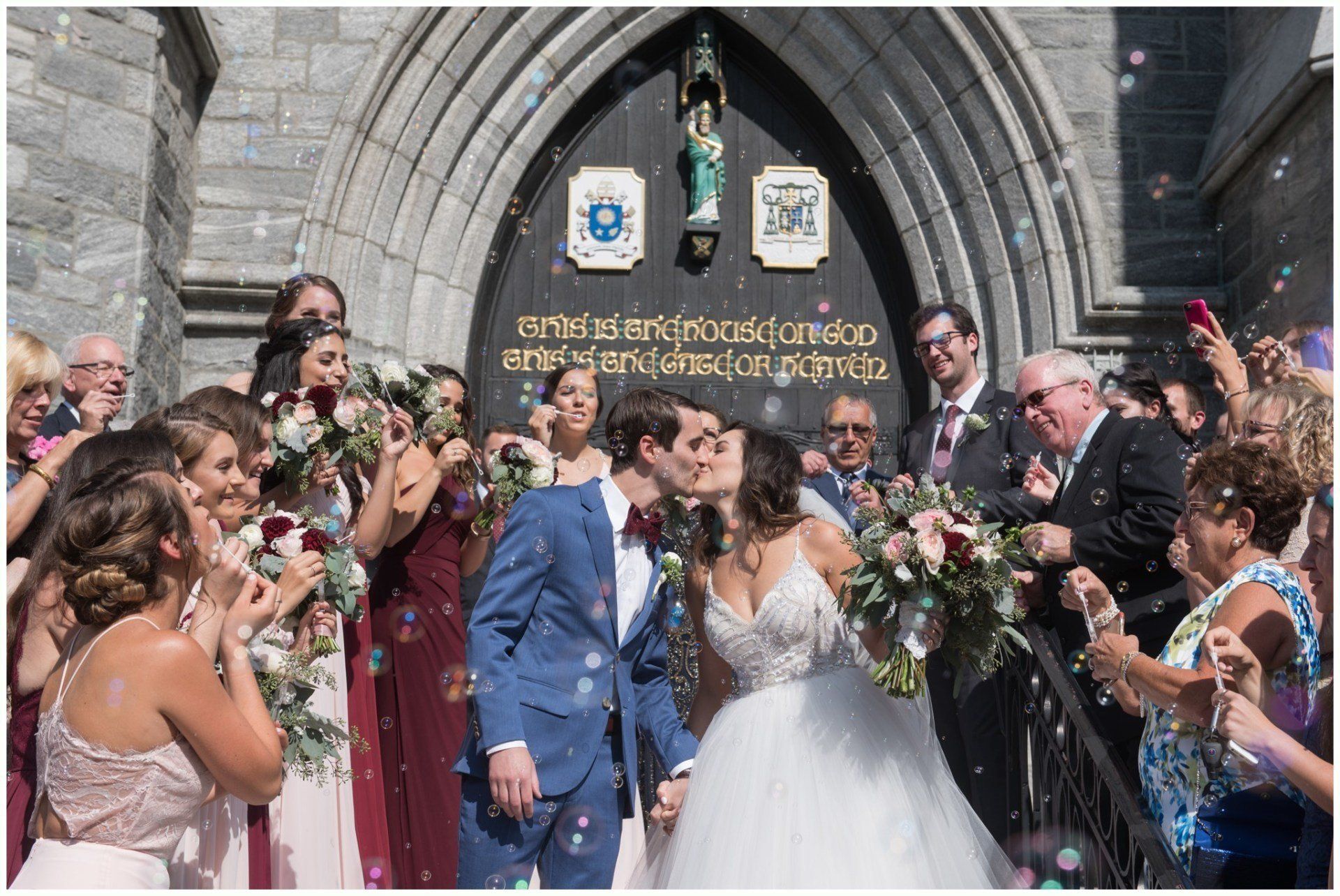 Wedding couple kissing outside church as guests cheer and shower them with confetti