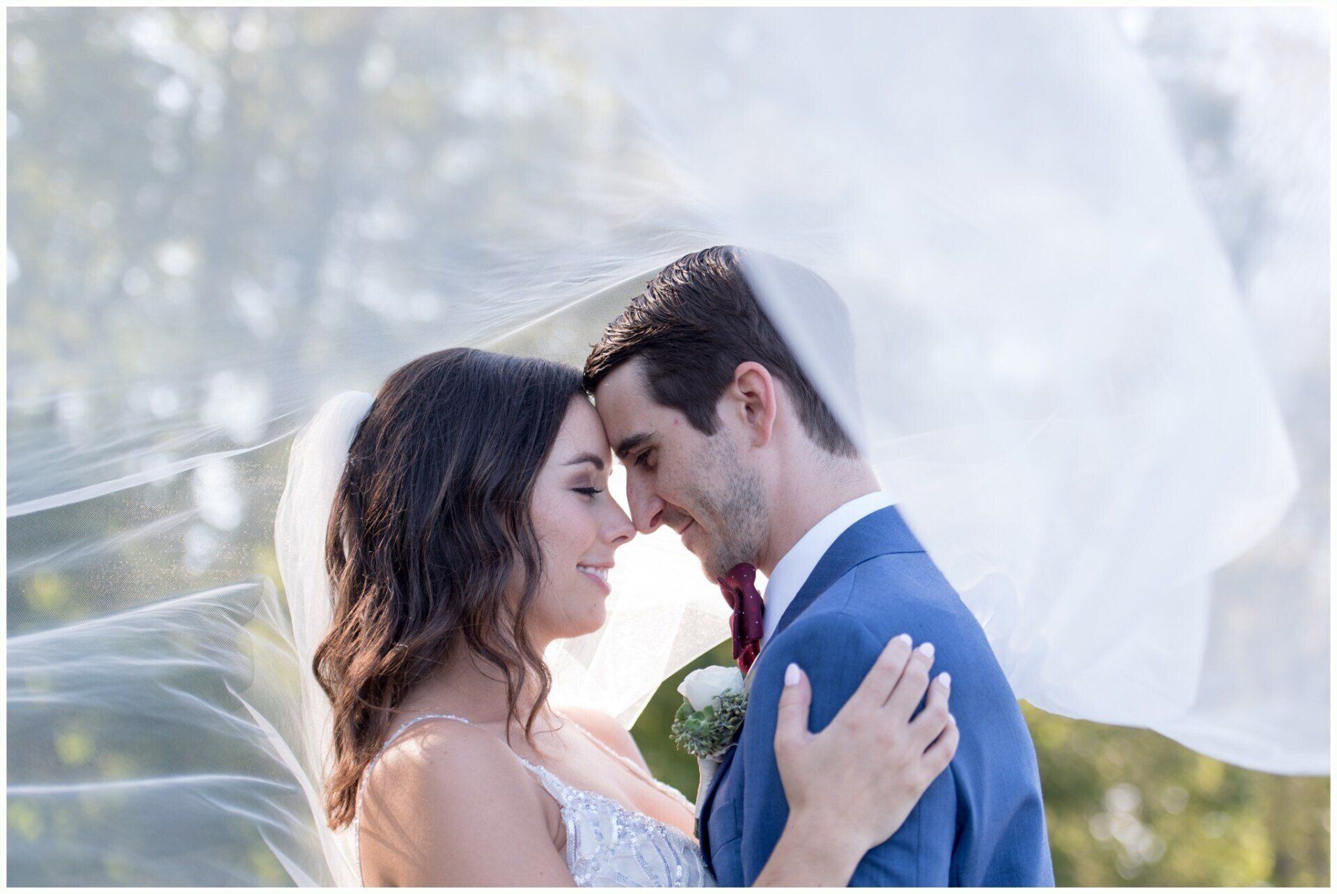 Couple embracing at a wedding, with the bride’s veil flowing in soft light.