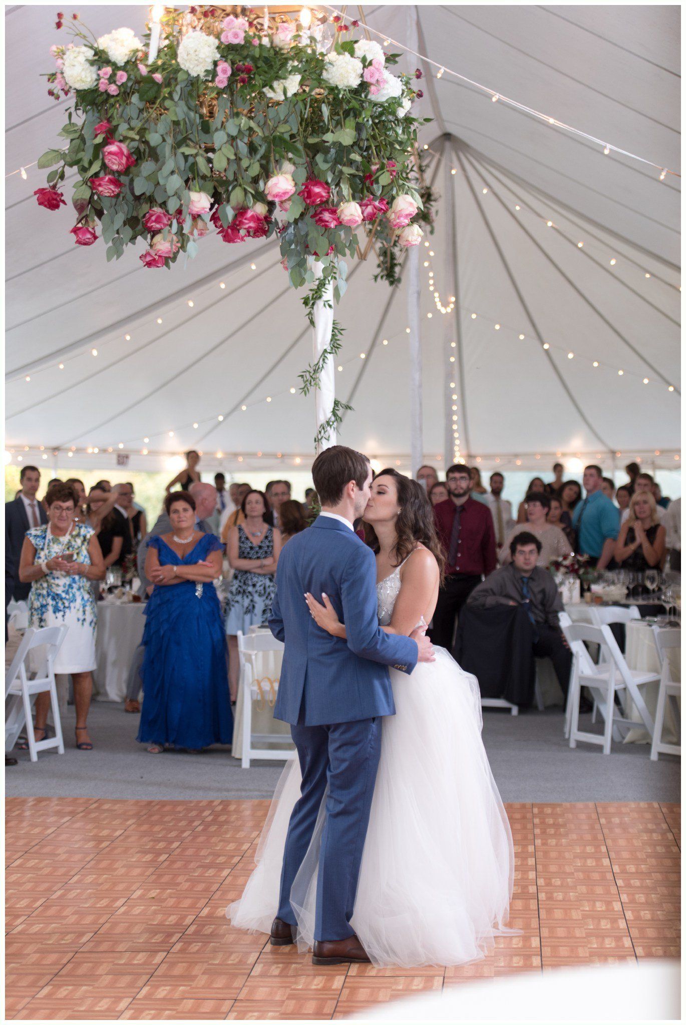 Bride and groom slow dancing under a floral tent at a wedding reception